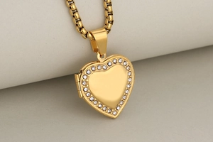 Detail of a gold heart pendant necklace with shimmering rhinestone inlay on a neutral background
