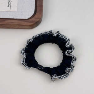 Detail of checkered plaid scrunchie with lace edge and elastic hair tie on a white surface