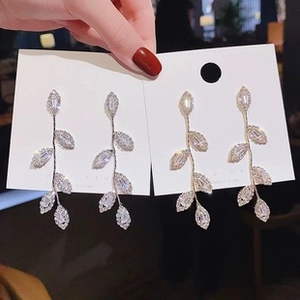 Detailed view of silver and gold leaf tassel earrings with sparkling marquise zircons