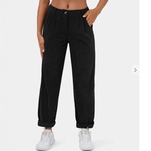 Detail view of black straight-leg casual trousers featuring pleated waist and cuffed hems