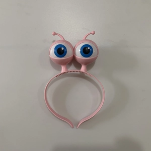 Detailed close-up of a pink LED alien headband featuring large cartoon glowing eyeballs