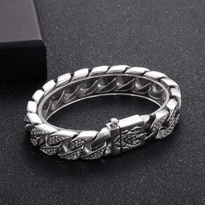 Macro shot of silver hip-hop Cuban link bracelet with rhinestone buckle on black texture