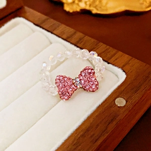 Macro shot of an elastic ring with pink crystal bow and beads in a wooden jewelry box