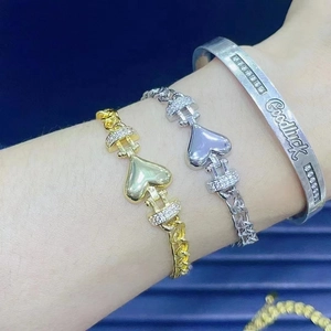Macro shot of 18K gold and silver heart bracelets with micro-set zircons on a model's wrist