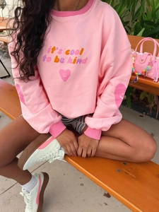 Pink crew neck sweatshirt with it's cool to be kind slogan and heart print