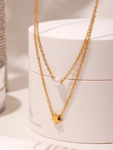 Detail of double-layered gold necklace featuring a white pearl and star-shaped pendant
