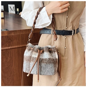 Detail of wool bucket bag featuring brown plaid pattern and leather drawstring closure