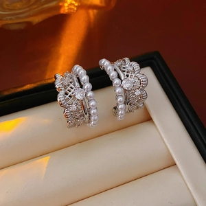 Detailed close-up of lace pearl silver earrings with sparkling zircon inlay in a jewelry box