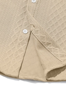 Detail of beige knit jacquard shirt showing textured fabric and white resin buttons
