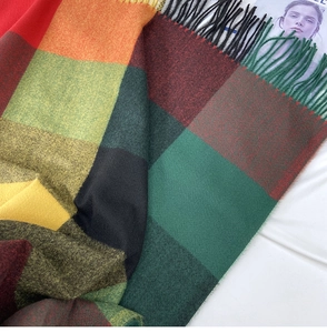 Close-up of vibrant colorful plaid scarf featuring soft fringe and thick knit texture