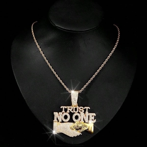 Macro detail of gold TRUST NO ONE hip hop pendant with sparkling diamonds and cuban chain