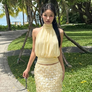 Close-up of light yellow backless halter top and sequined skirt in a resort setting
