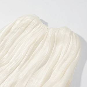 Macro shot of pleated cream fabric texture with pearlescent finish and small neck button