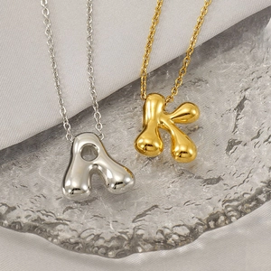 Macro detail of high-polish bubble letter pendants A and K in gold and silver finish