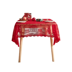 Red lace Christmas tablecloth featuring house and snowflake patterns on wooden table