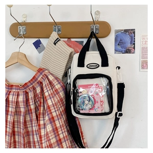 White canvas ita bag with a clear front display pocket hanging on a wooden wall hook