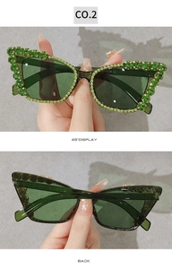 Detail view of cat eye sunglasses with green rhinestones and green tinted lenses