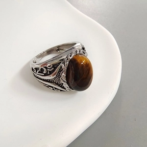 Macro detail of oval tiger eye stone with vintage floral carvings on silver band