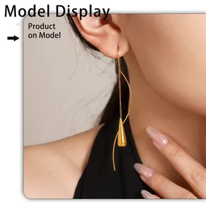 Close-up of elegant gold tassel earrings with teardrop pendants on a female model
