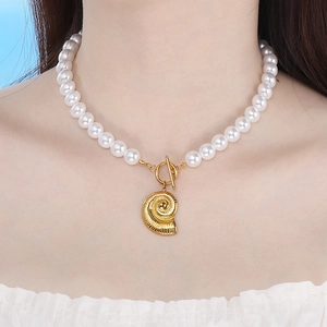 Detailed shot of pearl chain necklace with gold nautilus shell pendant on model's neck