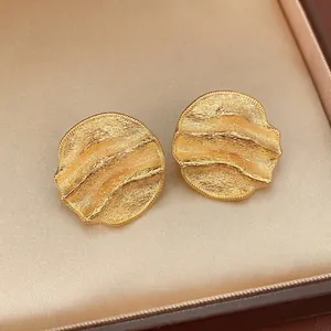 Polished gold plated irregular round ripple stud earrings on champagne silk in a gift box