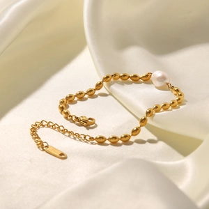 Macro detail of gold beads and natural freshwater pearl on a gold titanium steel bracelet