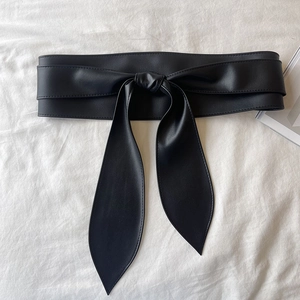 Détail d'une large ceinture en cuir PU noir avec nœud décoratif et coutures précises