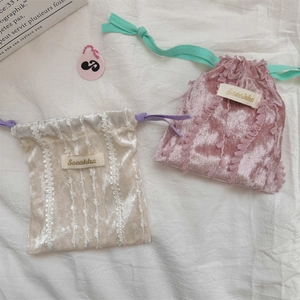 Detailed view of velvet drawstring pouches with lace trim and elegant brand label