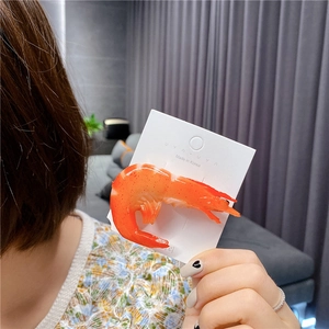 Macro shot of realistic cooked shrimp hair clip on white branded card for creative styling