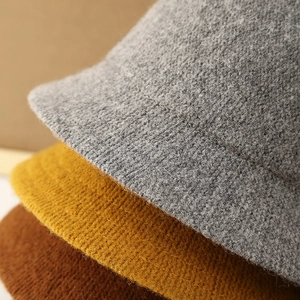 Macro detail of knitted bucket hats in grey, yellow, and brown showing warm thick texture