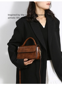 Borsa a tracolla vintage marrone con fibbia dorata indossata su sfondo bianco neutro