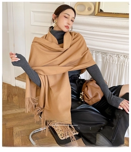 Close-up of soft camel cashmere-like scarf with fringe details worn as a long shawl
