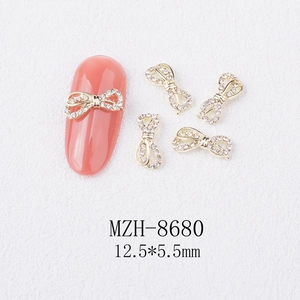 Macro detail of 12.5x5.5mm golden bow nail charms with white rhinestones on nail
