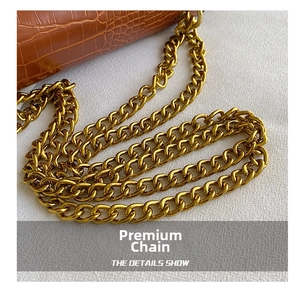 Detail shot of brown crocodile embossed leather and polished gold chain strap texture