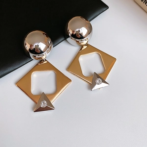 Detailed view of geometric mixed-metal earrings featuring gold hollow squares and rhinestones