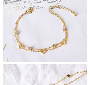 Detail of gold double-layer bracelet with hollow heart and star zircon charms