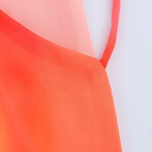 Detailed close-up of gradient orange and coral chiffon fabric texture on a long dress