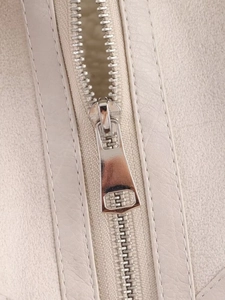 Detail of silver metal zipper and neat stitching on beige faux leather jacket