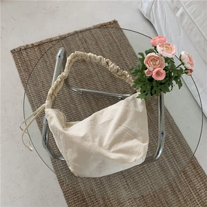 Dettaglio della borsa hobo beige con manico a pieghe e dettagli con coulisse