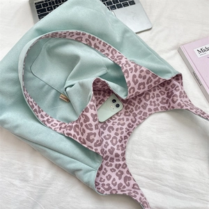 Detail view of mint green suede tote bag showing leopard print lining and inner pocket
