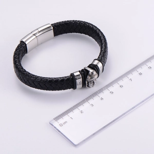 Dettaglio del bracciale in pelle intrecciata nera con testa di Buddha e chiusura magnetica