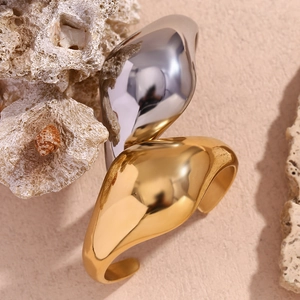 Close-up of chunky organic curved bangles in gold and silver with mirror polish