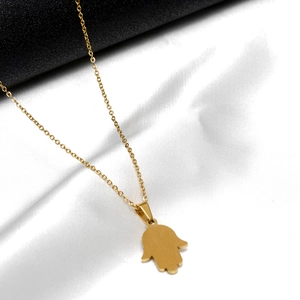 Macro detail of golden Hamsa Hand pendant with brushed metal finish and fine link chain