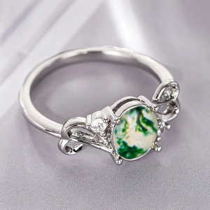 Macro detail of moss agate ring with silver bow-knot design and white zircon accents