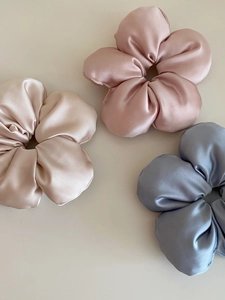 Detailed view of satin floral hair ties in champagne, pink, and blue silk-like fabric