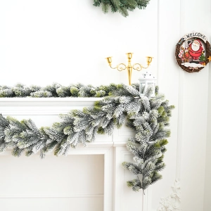 Artificial flocked Christmas garland with snow effect on white fireplace mantel decoration