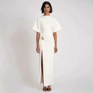 Détail d'une robe longue blanche à fronces avec fente latérale et boucle dorée à la taille