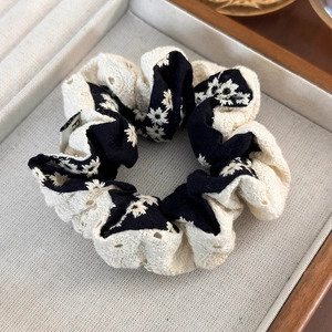 Detail of floral lace hair scrunchie in black and beige on a jewelry tray