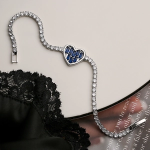 Detailed macro shot of silver heart tennis bracelet with deep blue center zircon stone