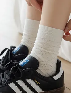Detail of off-white hollow diamond pattern mid-calf socks paired with black sneakers